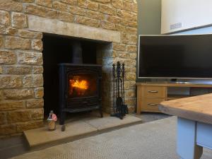 a living room with a fireplace with a television at The Stable at Woodhouse Farm in Montacute
