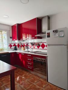una cucina con armadi rossi e frigorifero bianco di Mirador del Duque a Güéjar-Sierra