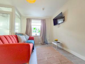 een woonkamer met een rode bank en een tv bij Copper Pine - Refurbished - Contractors & families in Dowlais