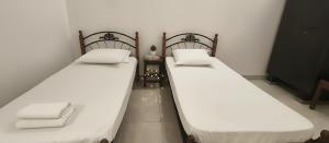 two beds in a room with white sheets and pillows at The Bro's code in Puducherry
