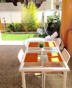 トッレ・ファロにあるTorre Faro Houseの白い椅子と植物が置かれたガラスのテーブル