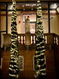 Una estatua frente a un edificio con un árbol de Navidad. en Hôtel Le Manoir, en Barr