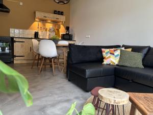 a living room with a black couch and a kitchen at De Emmahoeve in Holthone