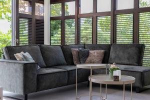 un sofá negro en una sala de estar con ventanas en Blue Bay's Tropical Escape, en Willemstad