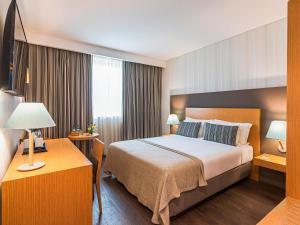 um quarto de hotel com uma cama e uma escrivaninha em Mercure Lisboa Almada em Almada