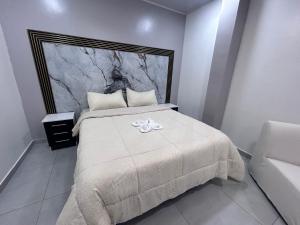 una camera da letto con un letto con un fiore bianco di Deramai a Santo Domingo de los Colorados