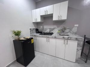 una cucina con mobili bianchi e un frigorifero nero di Deramai a Santo Domingo de los Colorados