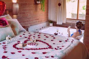 uma mulher sentada em uma banheira em uma cama com rosas em VELINN Pousadas Flor da Montanha em Monte Verde