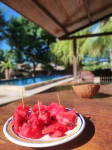 um prato de melancia em uma mesa perto de uma piscina em Maison Tropical em Paracuru