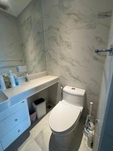 une salle de bains avec toilettes, lavabo et miroir dans l'établissement Beachfront Luxury Studio Condo near Marriot Naiyang 50 1, à Phuket