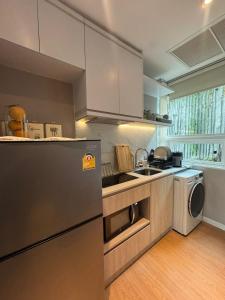 La cuisine est équipée d'un réfrigérateur en acier inoxydable et d'un lave-vaisselle. dans l'établissement Beachfront Luxury Studio Condo near Marriot Naiyang 50 1, à Phuket