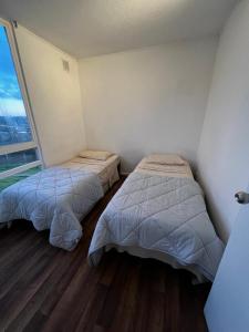 two beds in a room with a large window at Beautiful Portal Santo Domingo Apartment in San Antonio