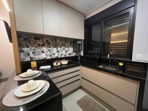 a kitchen with black counter tops and white appliances at Haven Residence in Uberlândia