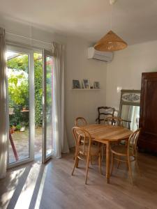 a dining room with a wooden table and chairs at La petite maison près de la mer, avec jardin , parking et clim in La Ciotat