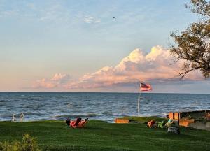 a beach with a flag and people sitting on the grass at SeaSide Lake-Front Cottage in Madison