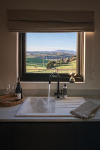 a kitchen sink with a window with a view of a field at The Byre, Summerhill Farm Stays in Balmaclellan