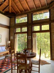 a living room with a table and chairs and windows at Guest House Tânia Alves in Pratinha