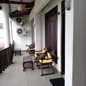 grupa krzeseł ustawiona na ganku z drzwiami w obiekcie Villa Tropi Lanka w mieście Unawatuna