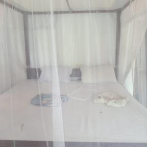 2 łóżka w pokoju z białymi zasłonami w obiekcie Villa Tropi Lanka w mieście Unawatuna