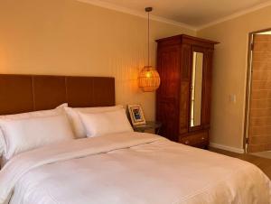 a bedroom with a large bed with white sheets at Mimosa Cottage in Cape Town
