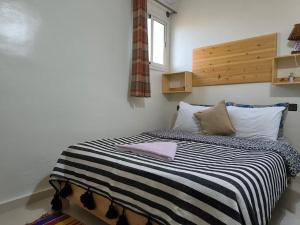 シディ・カウキにあるASGUN Roomのベッドルーム1室(ストライプ毛布付きのベッド1台付)