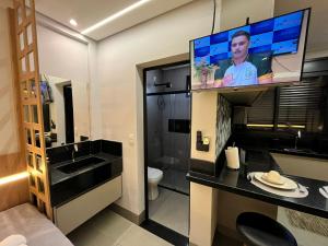 a bathroom with a toilet and a tv on the wall at Haven Residence in Uberlândia