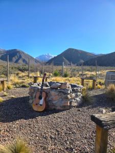 a guitar is sitting next to a stone wall at Puesto El Arroyito in Tunuyán