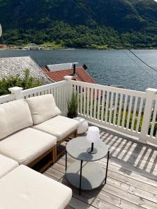 Un porche con un sofá y una mesa y agua. en Sjarmerende perle med utsikt mot fjorden, en Sogndal