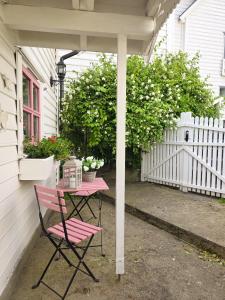 Una mesa rosa y una silla debajo de un porche. en Sjarmerende perle med utsikt mot fjorden, en Sogndal