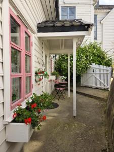 Un porche de una casa con una puerta rosa y flores. en Sjarmerende perle med utsikt mot fjorden, en Sogndal