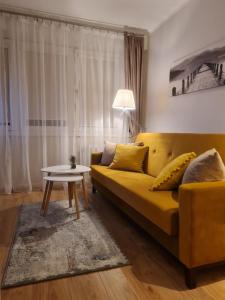 ein Wohnzimmer mit einem gelben Sofa und einem Tisch in der Unterkunft Apartament Toruń Orbita bezpłatny parking in Toruń