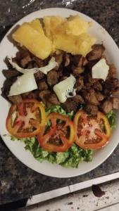 a plate of food with tomatoes and other foods at Caribe Palace Hotel Samambaia in Brasilia