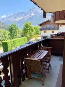 patio con mesa de madera y sillas en el balcón en Les Grands Tetras, en Les Chavants