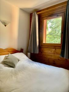 Un dormitorio con una cama blanca con una ventana. en Les Grands Tetras, en Les Chavants