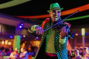 a man dressed as a clown playing a violin at Riu Palace Mexico - Adults Only - All Inclusive in Playa del Carmen