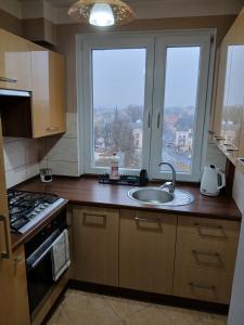 a kitchen with a sink and two large windows at Apartament Piła Wita in Piła