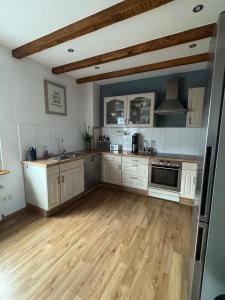 a large kitchen with wooden floors and white cabinets at Ferienhaus Auf der Drossel in Gevelsberg +10 photos
