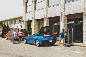 梅迪辛哈特梅迪辛哈特贝蒙特旅馆套房酒店的一群人站在一辆引擎盖敞开的蓝色汽车旁。