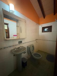 Un baño con inodoro, lavabo y espejo. en Casa jardin, en Luque