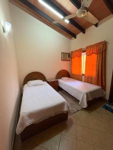 2 camas en una habitación con cortinas naranjas en Casa jardin, en Luque