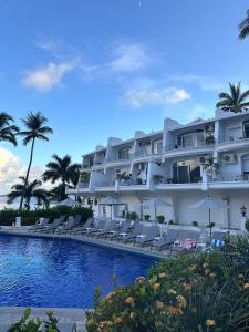 a large white hotel with chairs and a swimming pool at Santorini, loft frente al mar in Manzanillo