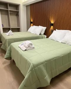 two beds with green sheets and towels on them at LAS CONDES Hotel in Tacna