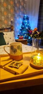 a table with a coffee cup and a christmas tree at Home away from home in Aberdeen