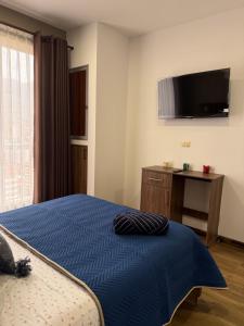 a bedroom with a bed and a tv on the wall at El departamento de Verito in Cochabamba