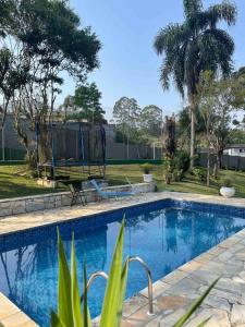 a swimming pool in a yard with palm trees at Chácara Canto Dos Pinheiros in Vargem Grande Paulista