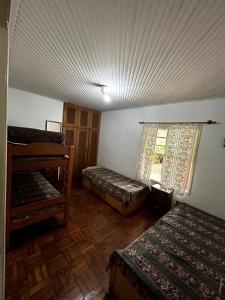 a room with two beds and a window in it at Chácara Canto Dos Pinheiros in Vargem Grande Paulista