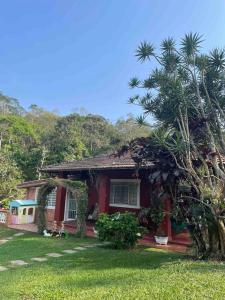 a red house with a palm tree in front of it at Chácara Canto Dos Pinheiros in Vargem Grande Paulista