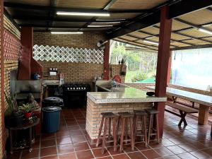 an outdoor kitchen with a counter and bar stools at Chácara Canto Dos Pinheiros in Vargem Grande Paulista
