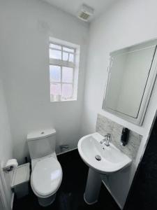 Un baño blanco con inodoro y lavabo. en TBH Hotel, en Barking