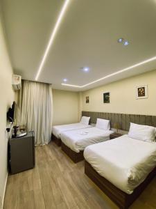 Una habitación de hotel con dos camas y un televisor. en Anyma Pyramids View Inn, en El Cairo